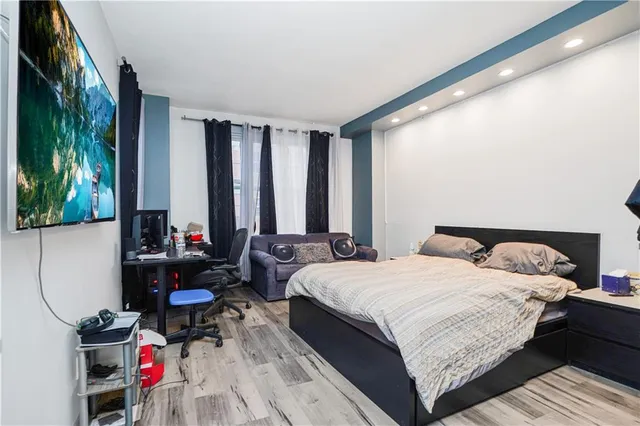 a bedroom with a bed a dresser and a large window