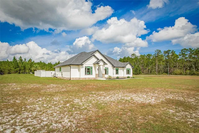 a front view of a house with a yard and large trees