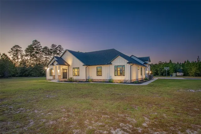 a view of a house with a big yard and large trees