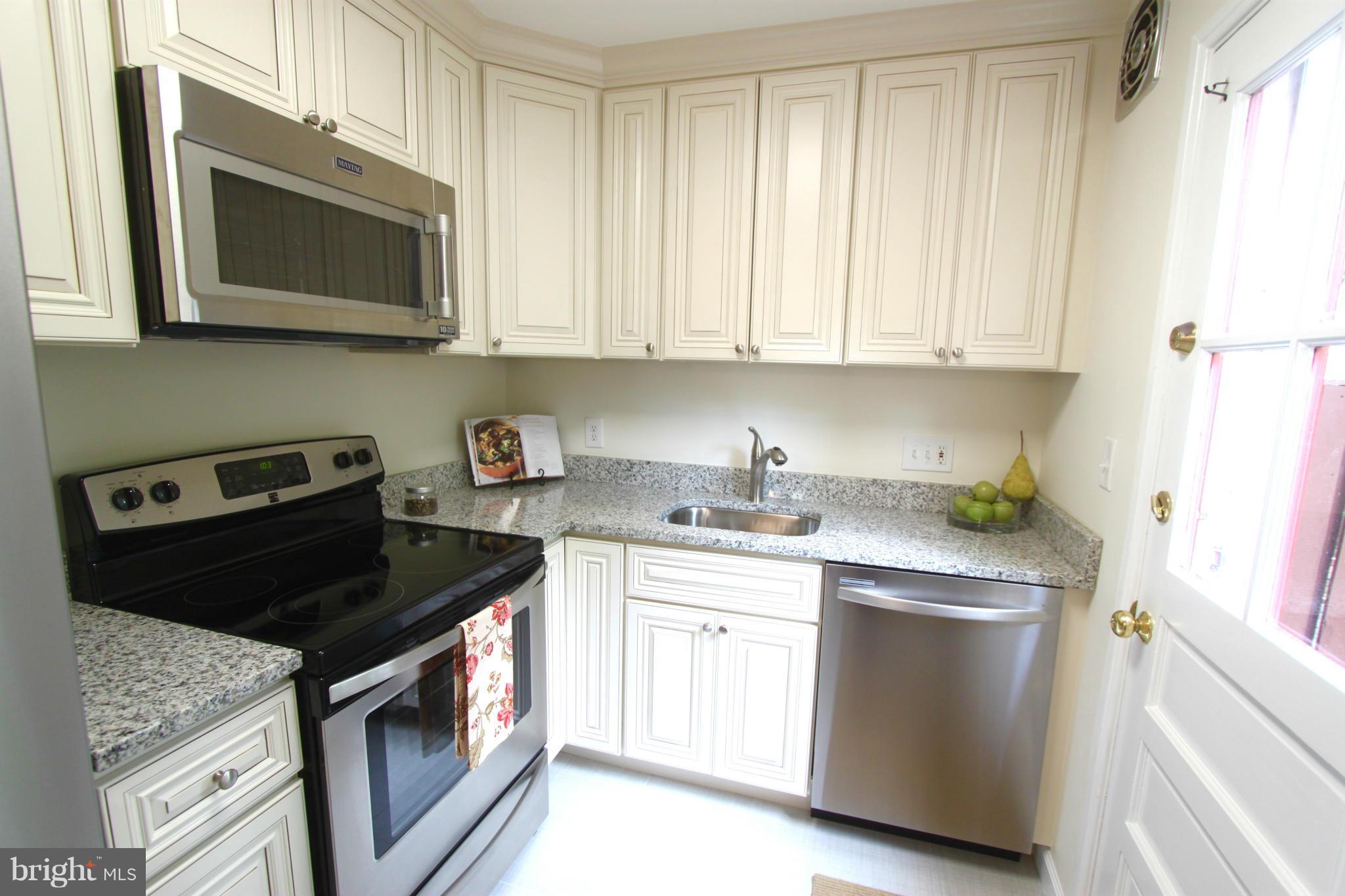 a kitchen with stainless steel appliances granite countertop white cabinets a stove top oven a sink and dishwasher