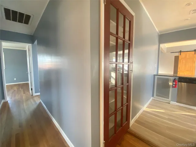 a view of a hallway with wooden floor and a bathroom