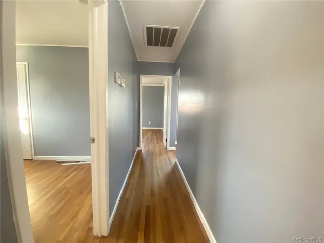 a view of a hallway with wooden floor and a bathroom