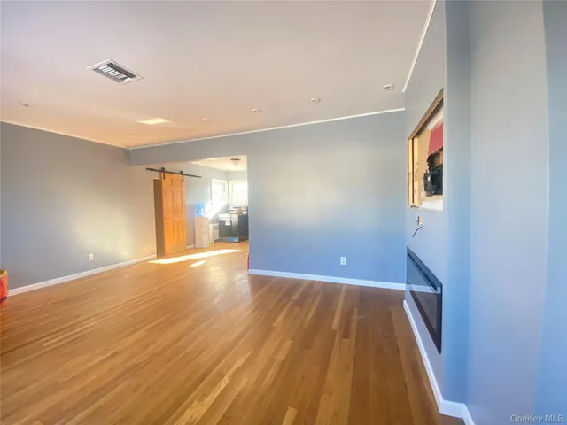 a view of a hallway with wooden floor and a bathroom