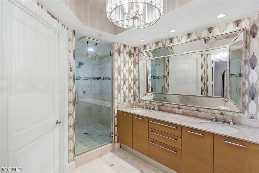 13675 Vanderbilt Drive, Unit 406 Naples, FL 34110 - Photo 18 of 43 a bathroom with a shower sink and mirror