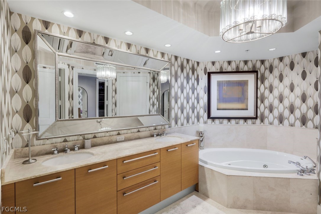 13675 Vanderbilt Drive, Unit 406 Naples, FL 34110 - Photo 19 of 43 a bathroom with a bathtub a double vanity sink and mirror