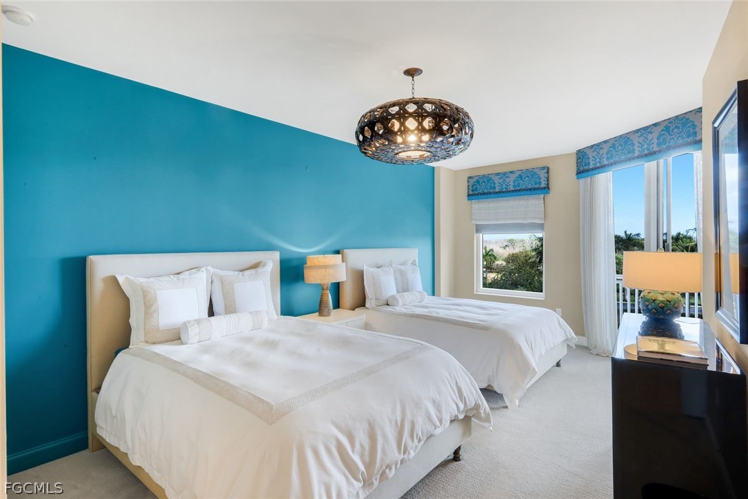 13675 Vanderbilt Drive, Unit 406 Naples, FL 34110 - Photo 20 of 43 a bedroom with a bed and a chandelier