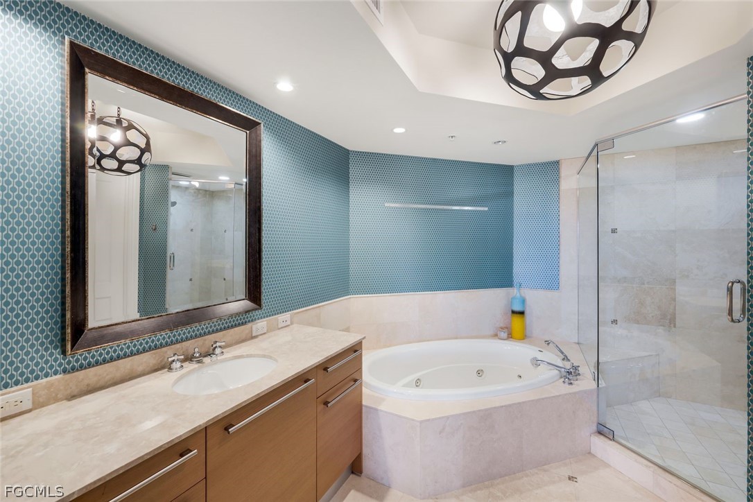 13675 Vanderbilt Drive, Unit 406 Naples, FL 34110 - Photo 21 of 43 a bathroom with a tub sink and mirror