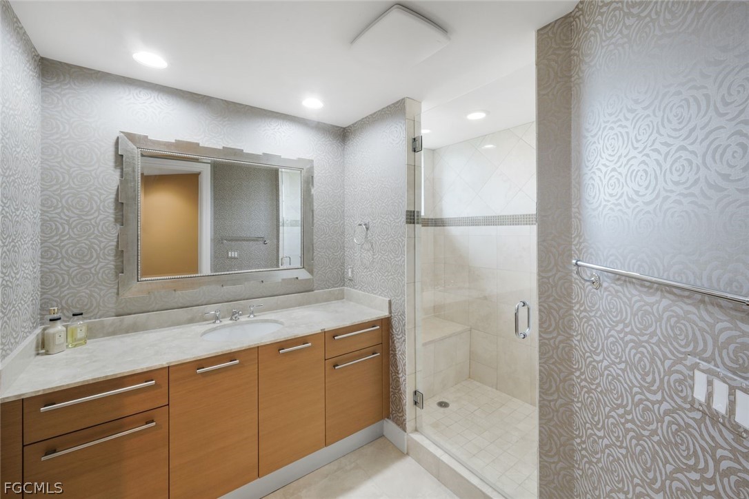 13675 Vanderbilt Drive, Unit 406 Naples, FL 34110 - Photo 23 of 43 a bathroom with a granite countertop sink mirror and a shower