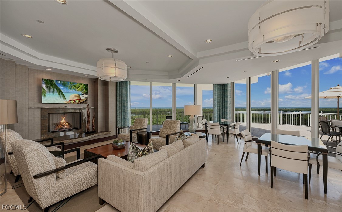 13675 Vanderbilt Drive, Unit 406 Naples, FL 34110 - Photo 39 of 43 a living room with furniture large windows and a fireplace