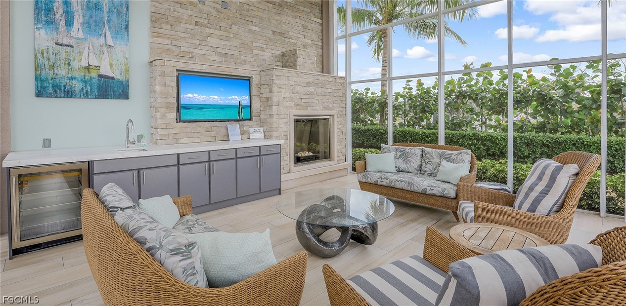 13675 Vanderbilt Drive, Unit 406 Naples, FL 34110 - Photo 40 of 43 a living room with furniture a fireplace and a floor to ceiling window