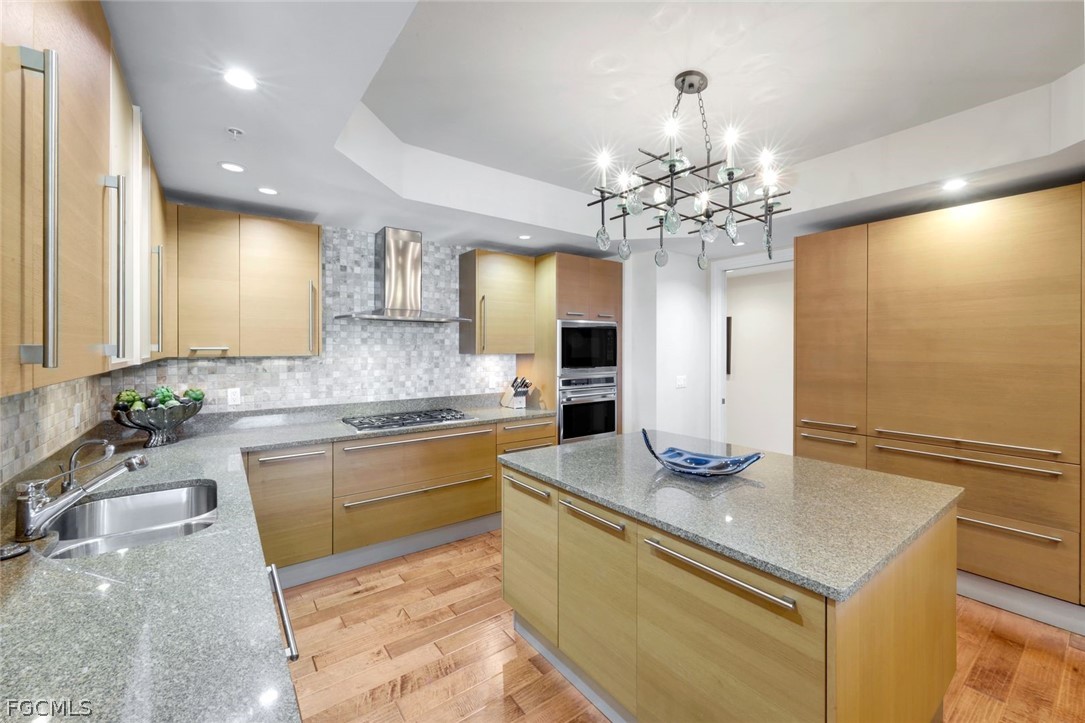 13675 Vanderbilt Drive, Unit 406 Naples, FL 34110 - Photo 10 of 43 a kitchen with kitchen island granite countertop a sink a counter top space cabinets and stainless steel appliances