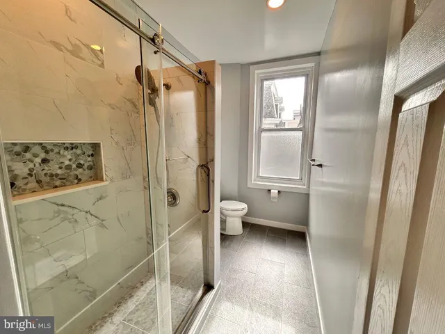 a bathroom with a granite countertop shower a toilet and a sink