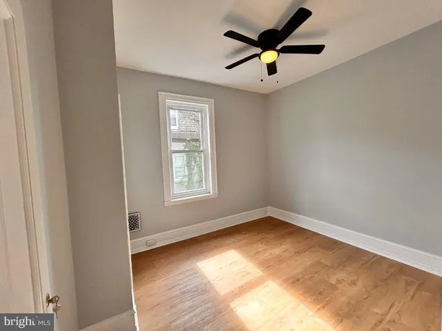 an empty room with ceiling fan and window