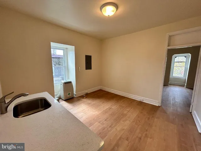 a view of an empty room with window and wooden floor