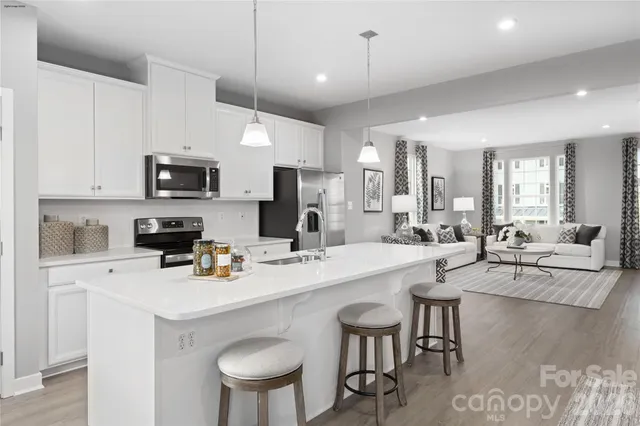 a kitchen with a sink a stove a refrigerator and white cabinets with wooden floor