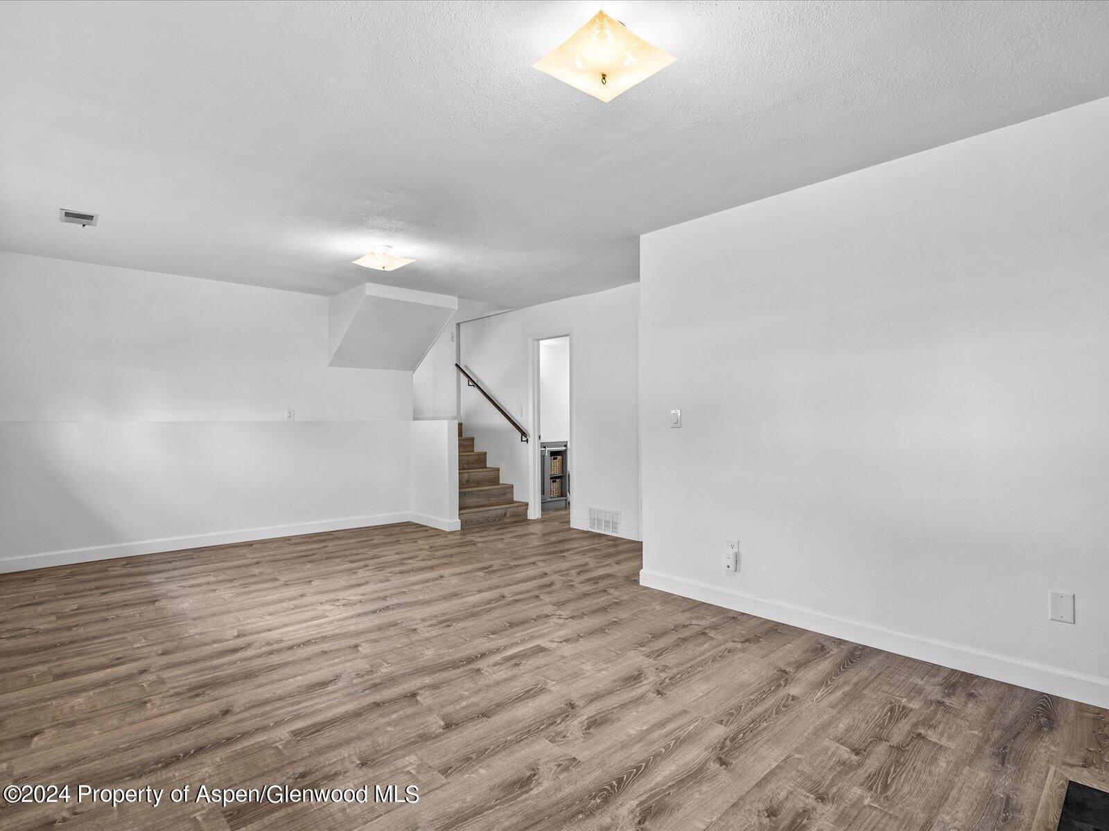 1178 East 8th Street Rifle, CO 81650 - Photo 19 of 28 an empty room with wooden floor and windows