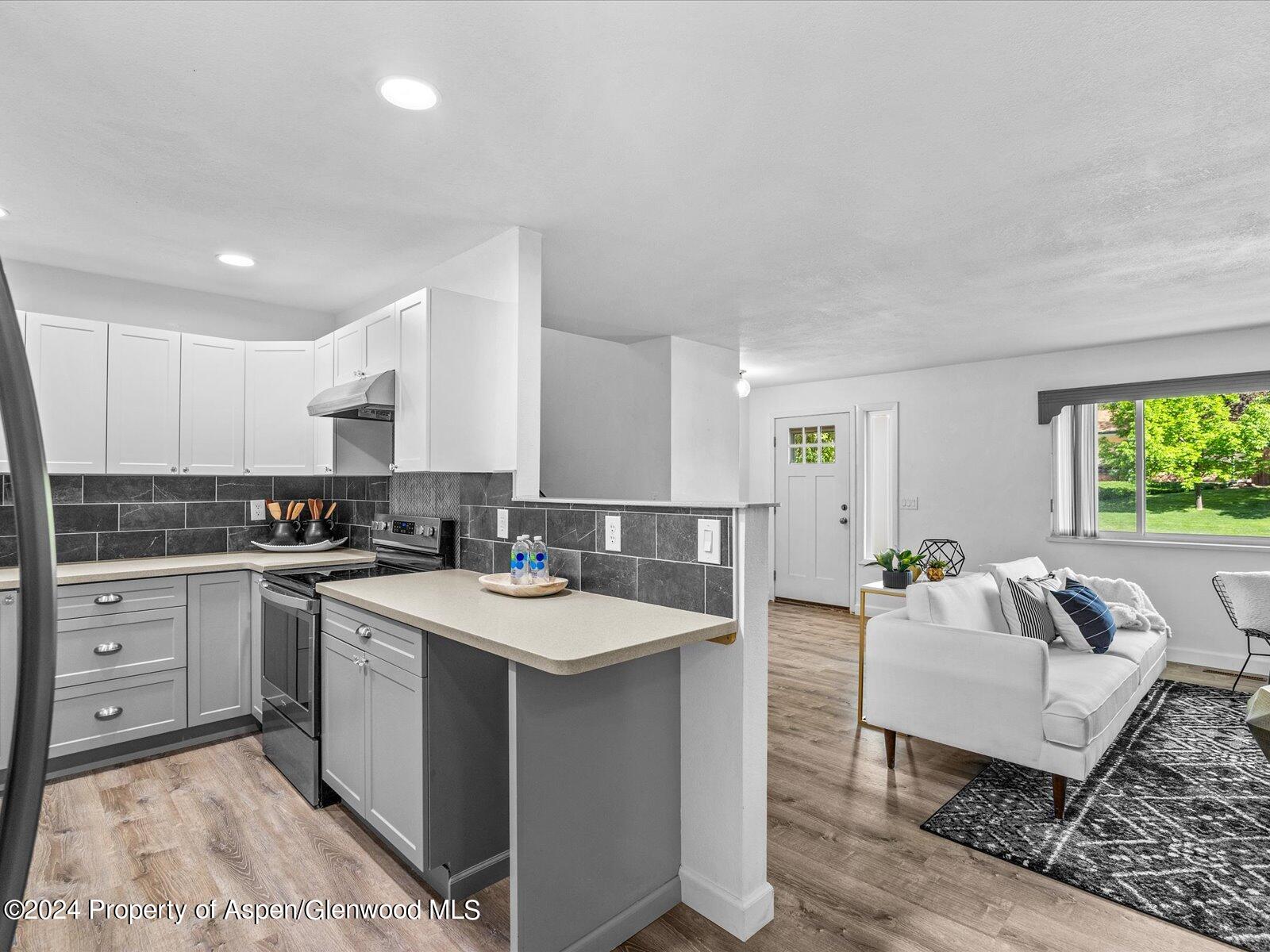 1178 East 8th Street Rifle, CO 81650 - Photo 10 of 28 a large white kitchen with a stove a sink a dining table and chairs