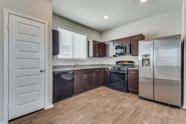 a kitchen with a refrigerator stove and wooden cabinets