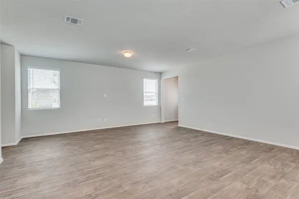a view of an empty room with a window and wooden floor