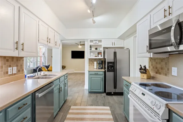 a kitchen with stainless steel appliances a stove refrigerator sink and microwave
