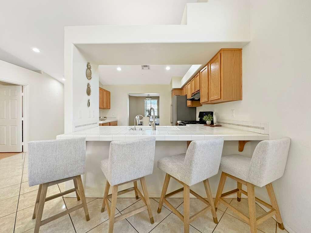 67755 Ontina Road Cathedral City, CA 92234 - Photo 13 of 30 a kitchen with stainless steel appliances kitchen island granite countertop a dining table chairs and a refrigerator