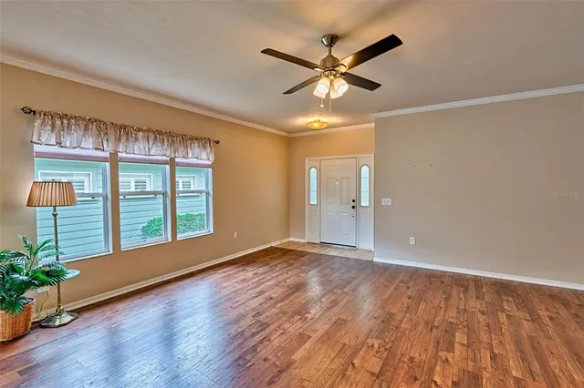 a view of an empty room with a window and wooden floor