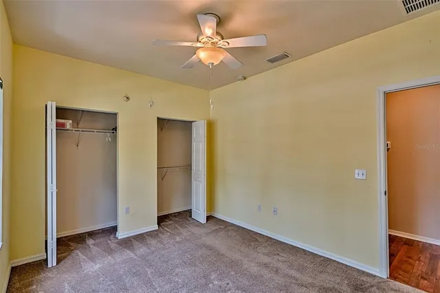 an empty room with closet and a ceiling fan