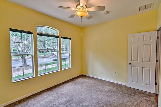 a view of an empty room with window and chandelier fan