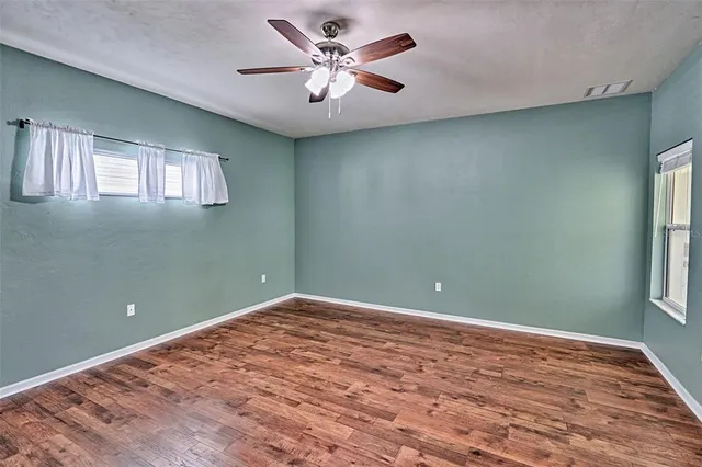 a view of empty room with window and ceiling fan