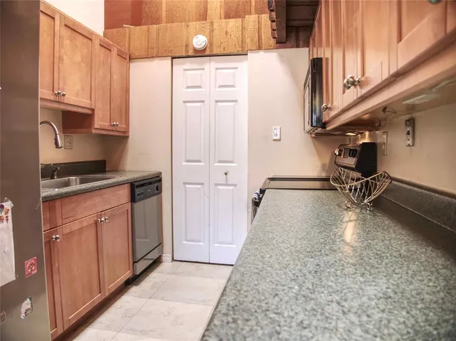 a kitchen with granite countertop a refrigerator a stove and white cabinets with wooden floor