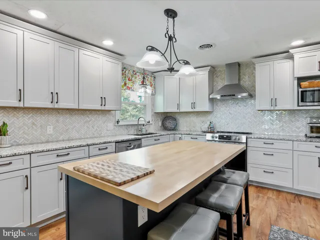 a kitchen with kitchen island granite countertop a sink a stove and white cabinets