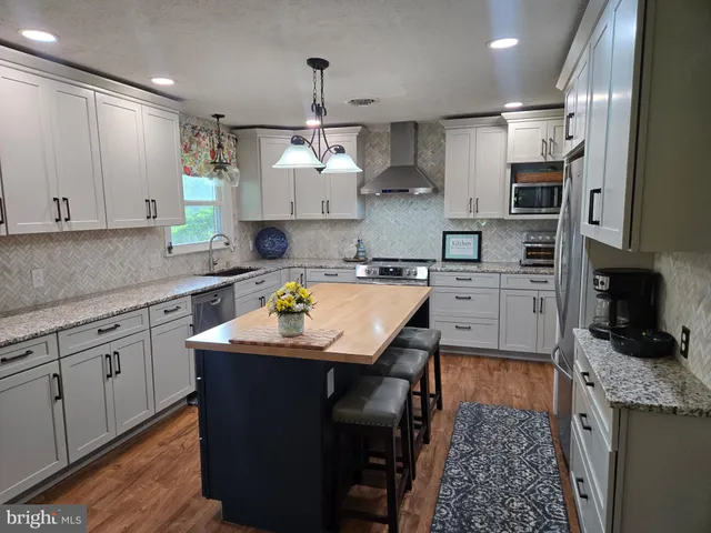 a kitchen with stainless steel appliances kitchen island granite countertop a sink a stove and cabinets