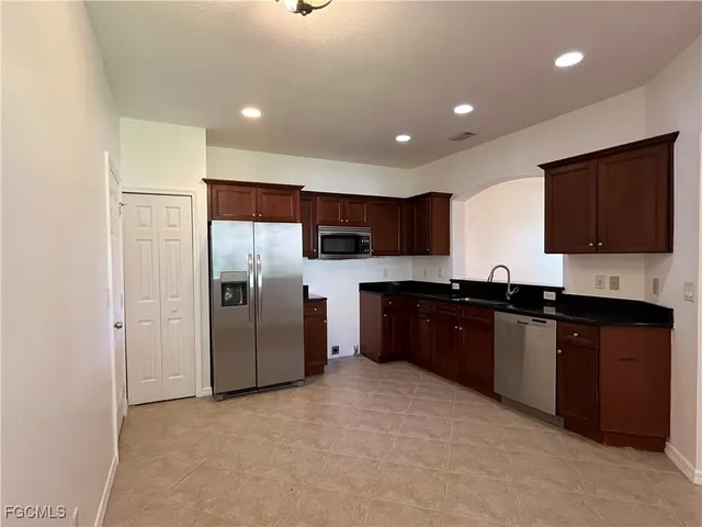 a large kitchen with stainless steel appliances granite countertop a refrigerator and a stove top oven