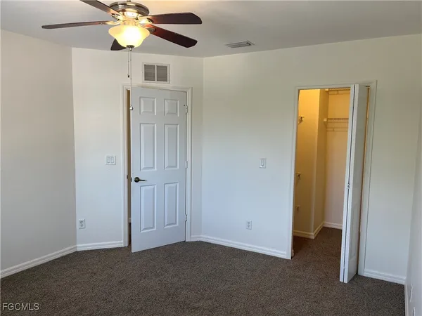 an empty room with closet and a chandelier fan