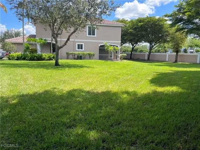 a view of house with a big yard and potted plants and large trees