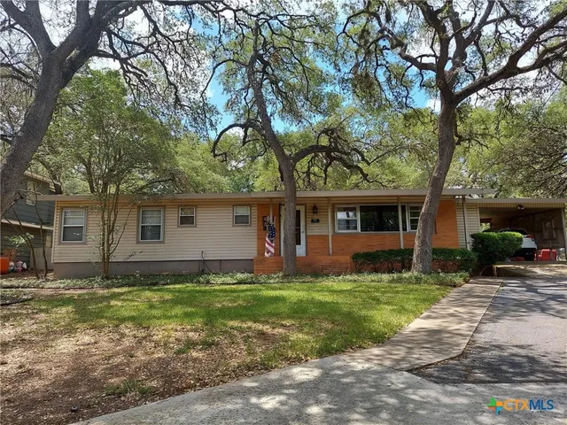 a front view of a house with a yard and trees