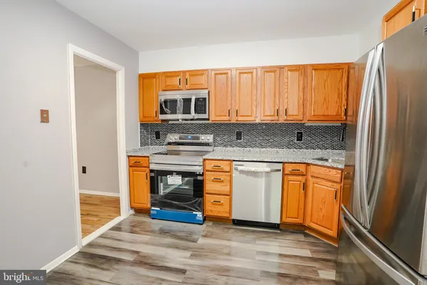 a kitchen with stainless steel appliances granite countertop a refrigerator a stove and a sink with wooden floor