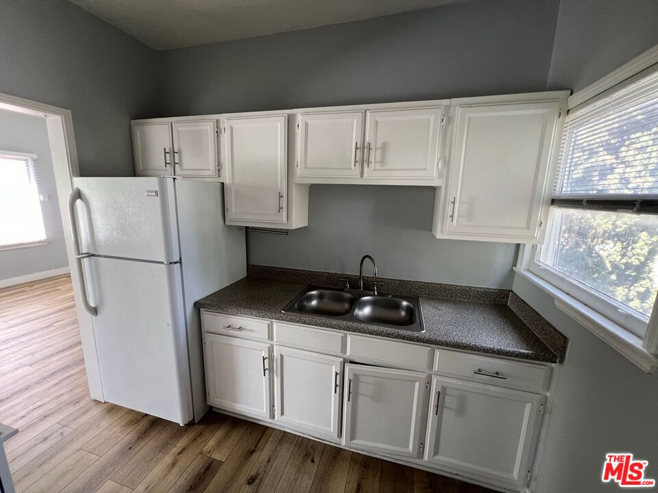 1217 Cedar Avenue Long Beach, CA 90813 - Photo 6 of 15 a kitchen with stainless steel appliances granite countertop a refrigerator sink and white cabinets