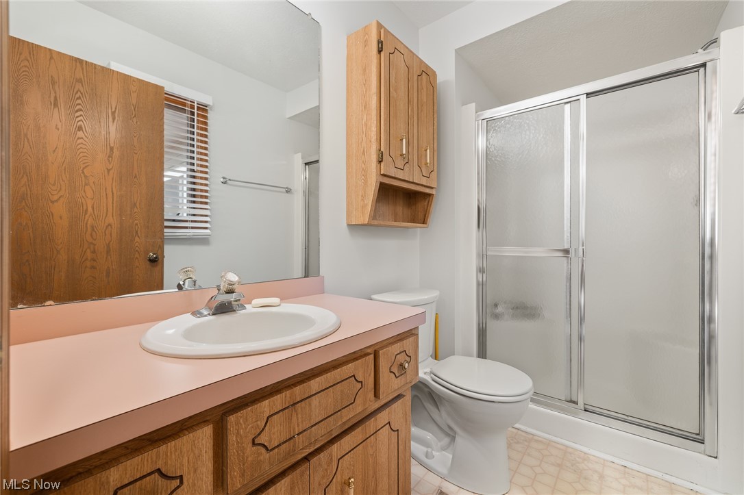 14495 Sheldon Road Cleveland, OH 44130 - Photo 13 of 27 Bathroom with tile floors, a shower with shower door, toilet, and oversized vanity