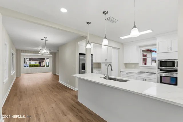 a kitchen with white cabinets and stainless steel appliances