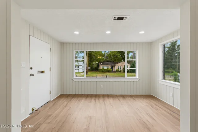 an empty room with a window and wooden floor