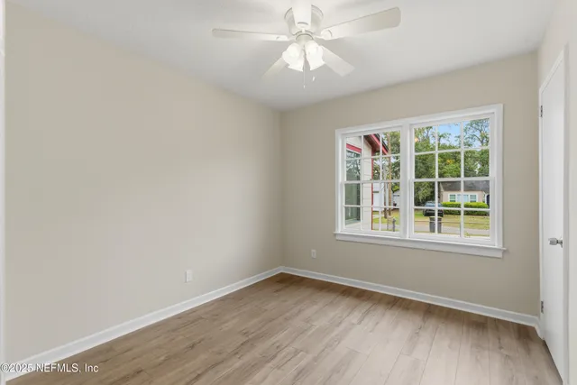 an empty room with a window and a ceiling fan
