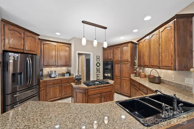 a kitchen with stainless steel appliances granite countertop a stove refrigerator sink and cabinets