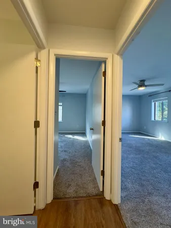 a view of a hallway with wooden floor and a living room