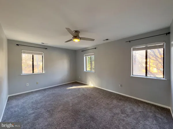 a view of an empty room with window and chandelier fan