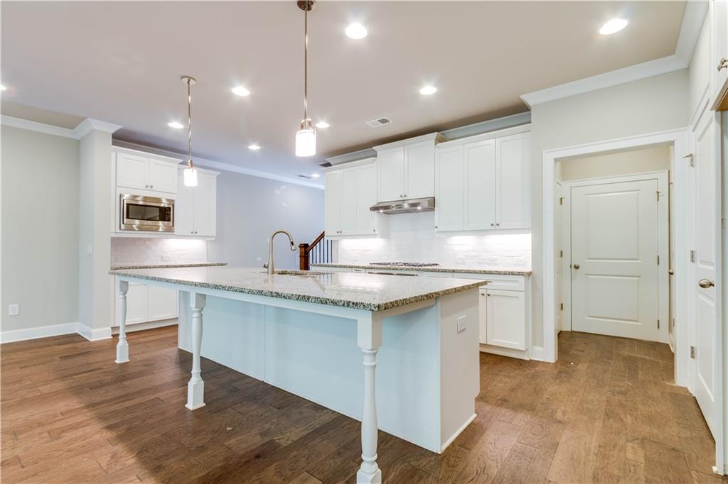 a kitchen with granite countertop a sink and white cabinets with wooden floor