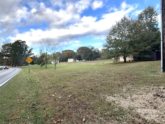 a view of a green field with trees in the background