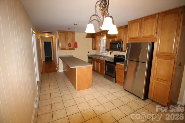 a kitchen with stainless steel appliances granite countertop a refrigerator a sink dishwasher and a stove with wooden cabinets