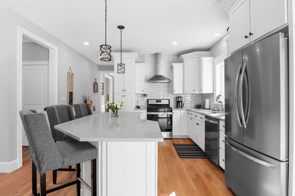 600 Wethersfield Street Rowley, MA 01969 - Photo 15 of 42 a kitchen with kitchen island a refrigerator a stove a dining table and chairs