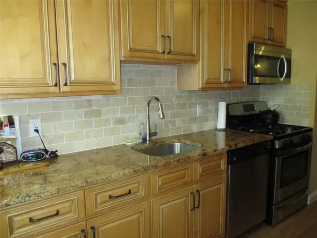 a kitchen with stainless steel appliances granite countertop a sink a stove and cabinets